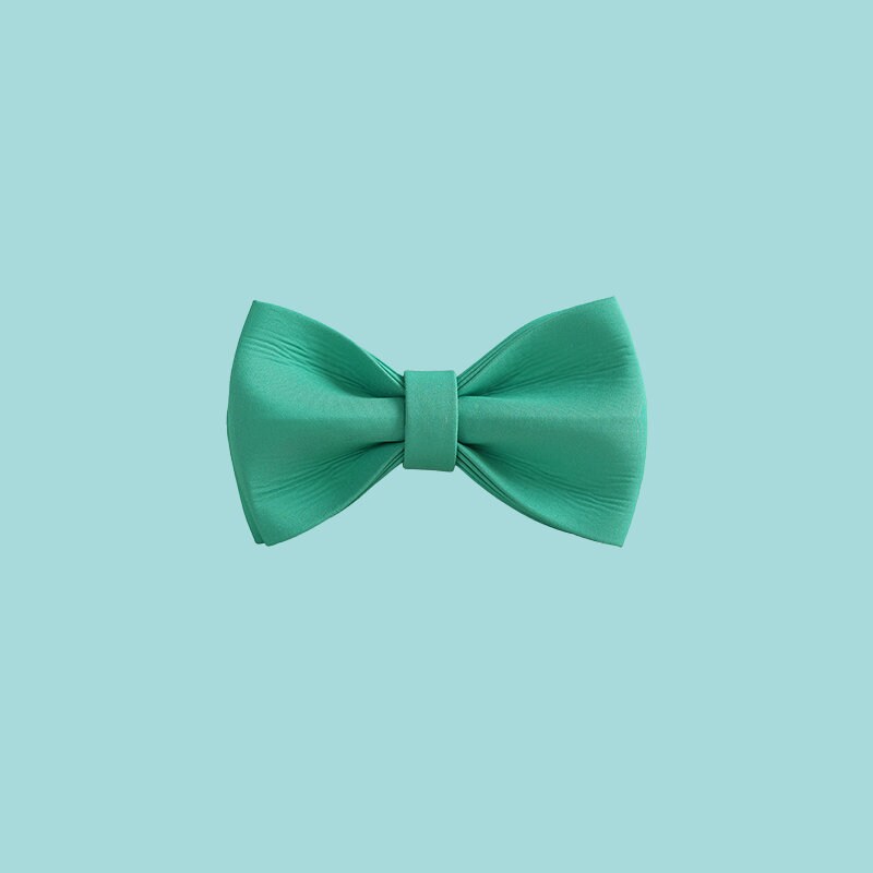 a green bow tie on a white wall